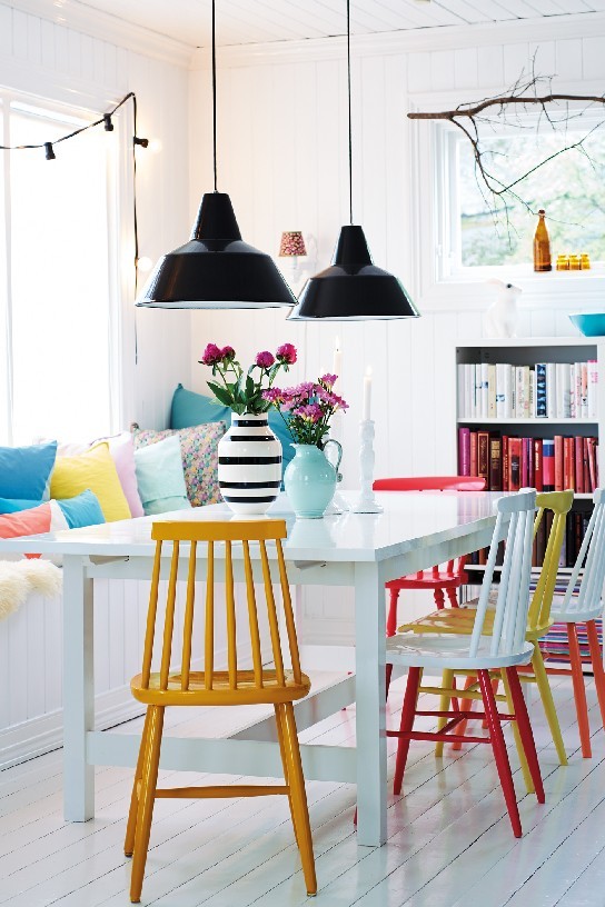 10 Happy Dinning Room Ideas to your Summer House A series of painted dining chairs, colour-coordinated books and paste-coloured cushions bright a bright and friendly atmosphere